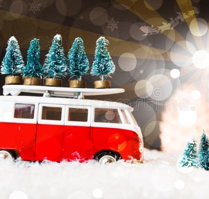 Toy red camper van with Christmas trees on the roof